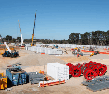 Plant installation in progress with construction cranes and materials on-site Construction site with cranes, containers, and equipment for large-scale plant installation under clear skies